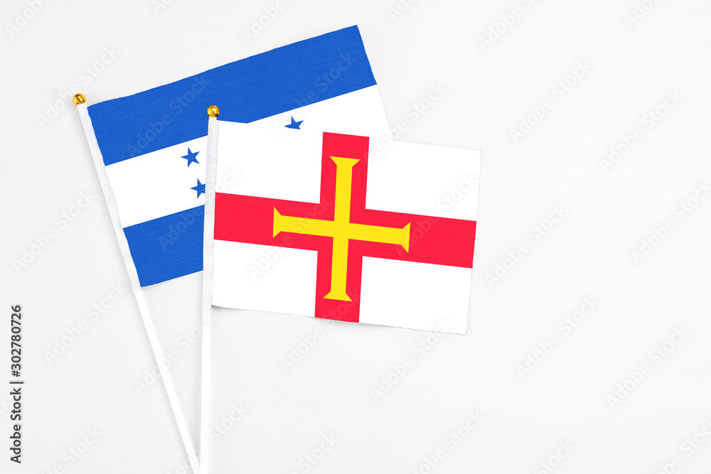 Guernsey and Honduras stick flags on white background. High quality fabric, miniature national flag. Peaceful global concept.White floor for copy space.