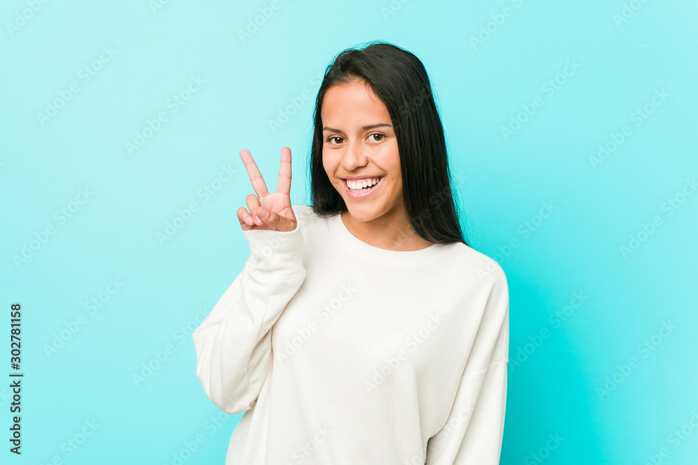 Young pretty hispanic woman showing victory sign and smiling broadly. Young pretty hispanic woman showing victory sign and smiling broadly.