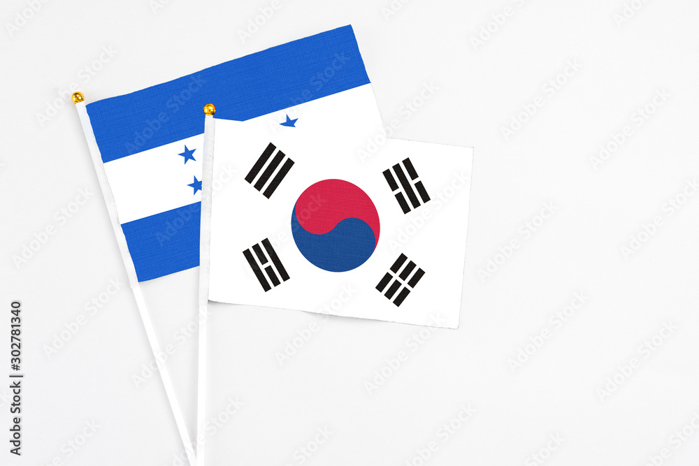 South Korea and Honduras stick flags on white background. High quality fabric, miniature national flag. Peaceful global concept.White floor for copy space.