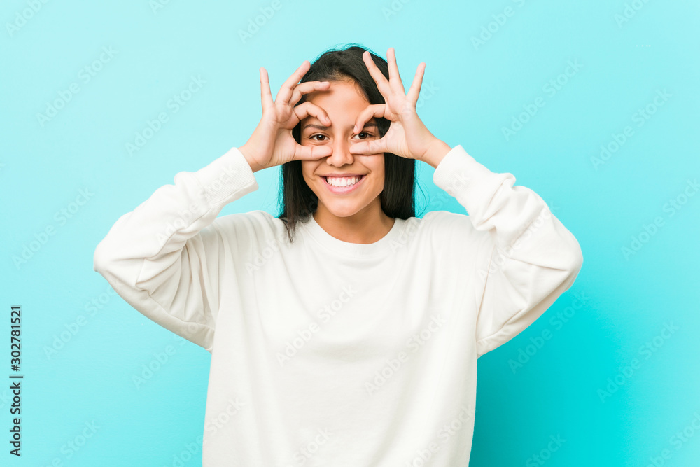 Young pretty hispanic woman showing okay sign over eyes Young pretty hispanic woman showing okay sign over eyes