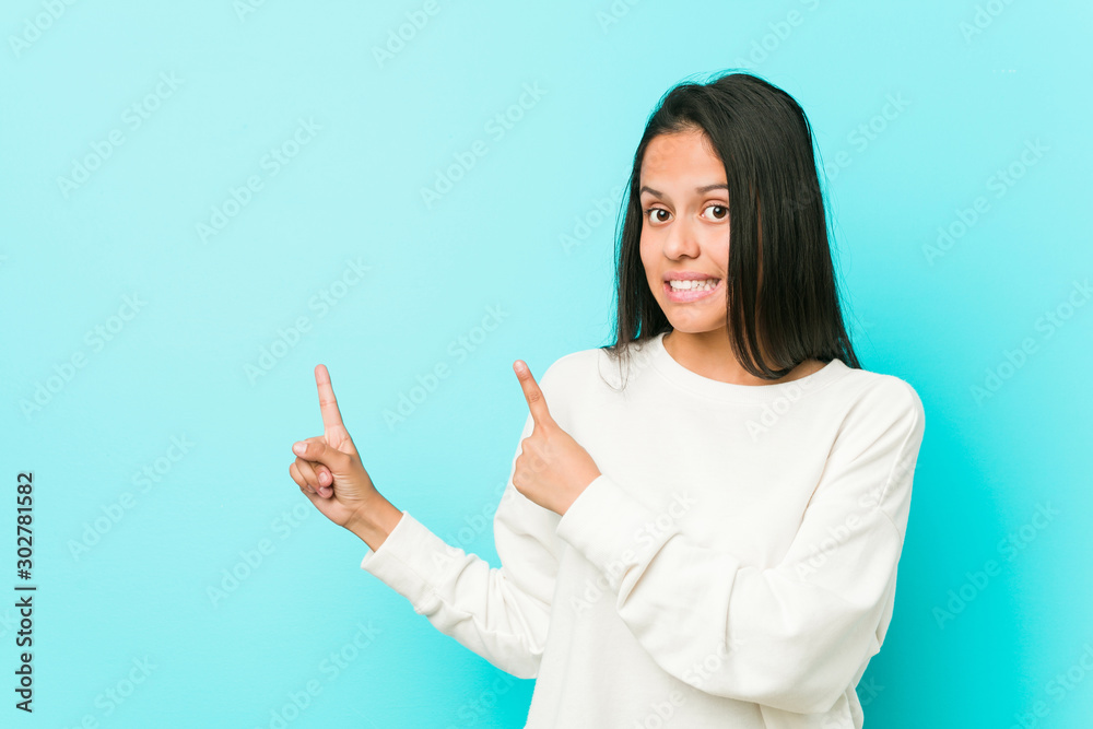 Young pretty hispanic woman shocked pointing with index fingers to a copy space. Young pretty hispanic woman shocked pointing with index fingers to a copy space.
