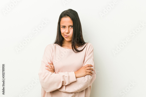 Young cute hispanic teenager woman frowning face in displeasure, keeps arms folded. © Asier