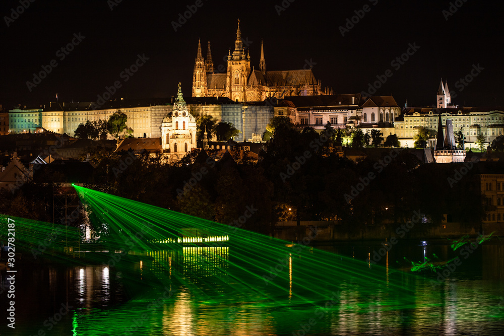Prague castle with Vltava river in the foreground at the rays of the green laser, Prague.