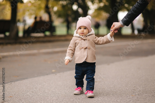 Cute little baby walking in the park with mother. Autumn