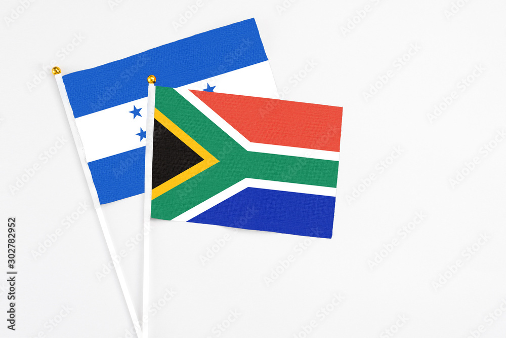 Fototapeta premium South Africa and Honduras stick flags on white background. High quality fabric, miniature national flag. Peaceful global concept.White floor for copy space.