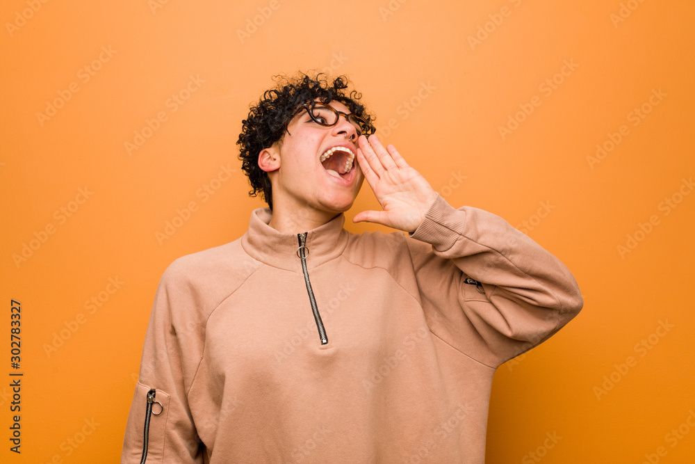 Young mixed african american woman against a brown background shouting and holding palm near opened mouth.