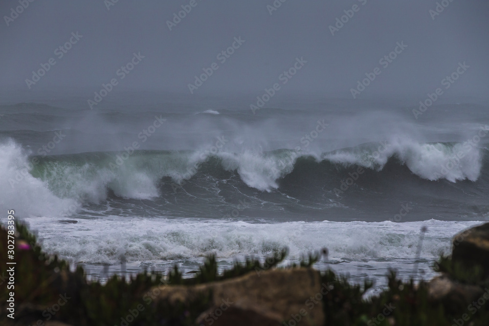 Storm at sea, storm warning on the coast. Thunderclouds and big sea waves during a storm. Restless sea during the rain. Storm at sea, storm warning on the coast. Thunderclouds and big sea waves during a storm. Restless sea during the rain.