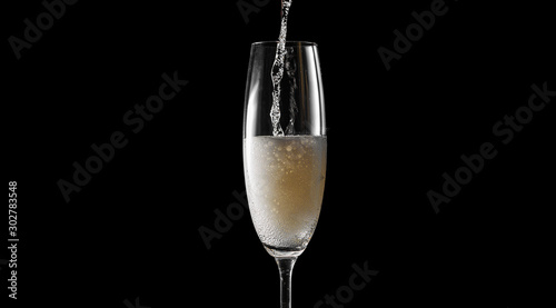 pour champagne into an empty glass. on a black background