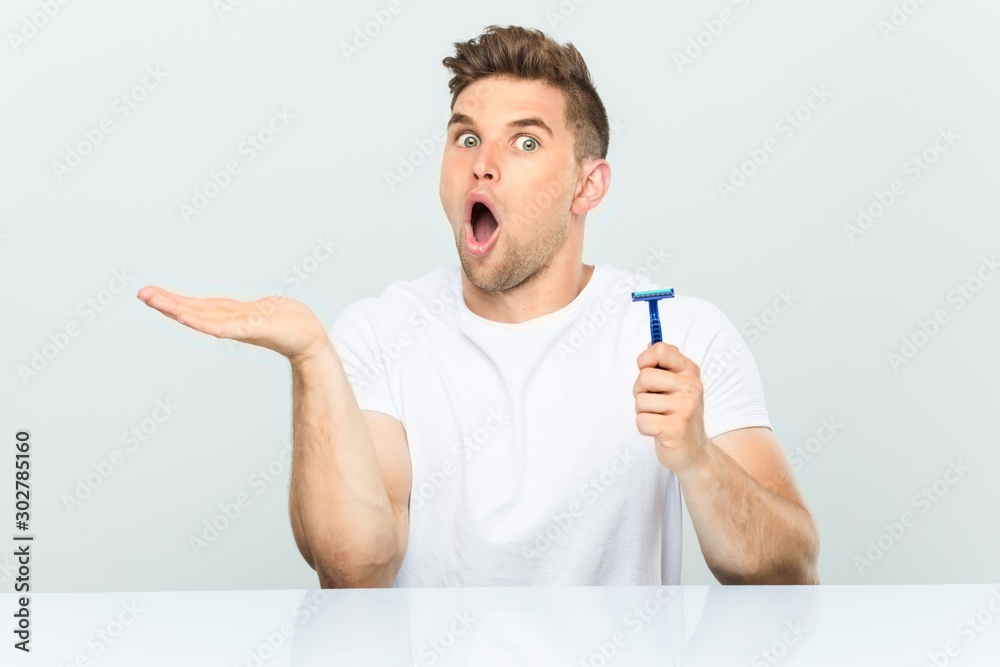 Young man holding a razor blade impressed holding copy space on palm. Young man holding a razor blade impressed holding copy space on palm.