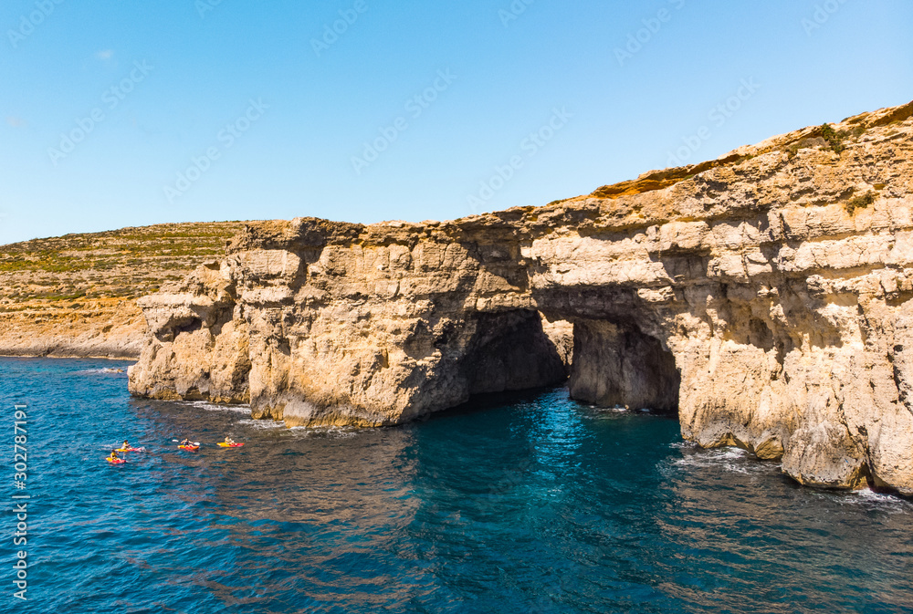 Group of kayakers and cave. Comino island. Drone landscape. Europe. Malta 