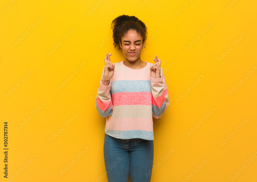 Young black african american girl with blue eyes crossing fingers for having luck Young black african american girl with blue eyes crossing fingers for having luck