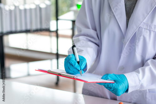 close up of scientist recording at note in lab