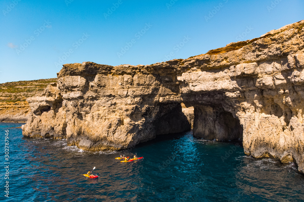 Group of kayakers under cave. Comino island. Drone landscape. Europe. Malta island 