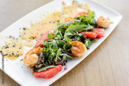 Delicious dish with grilled shrimps, slice grapefruit and arugula salad and spicy fried prawns. Restaurant menu, natural and organic food concept.