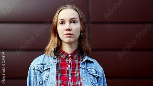 Emotions. Teenager. Young pretty white caucasian girl in casual jean jacket opposite dark modern backgroun on the street in the autumn.