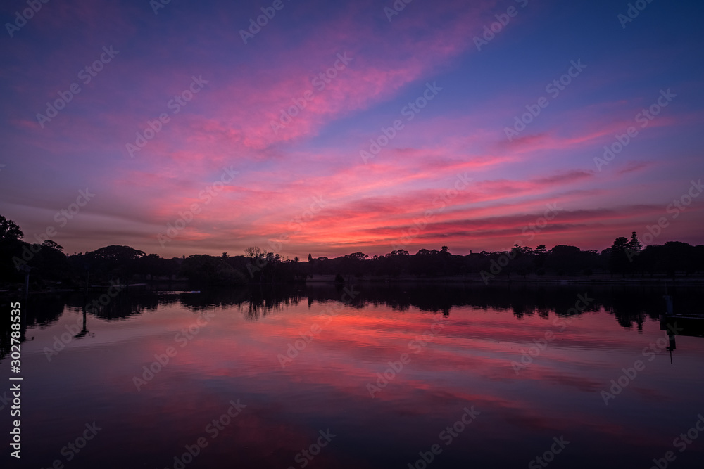 Obraz premium pink clouds at sunrise at park with lake