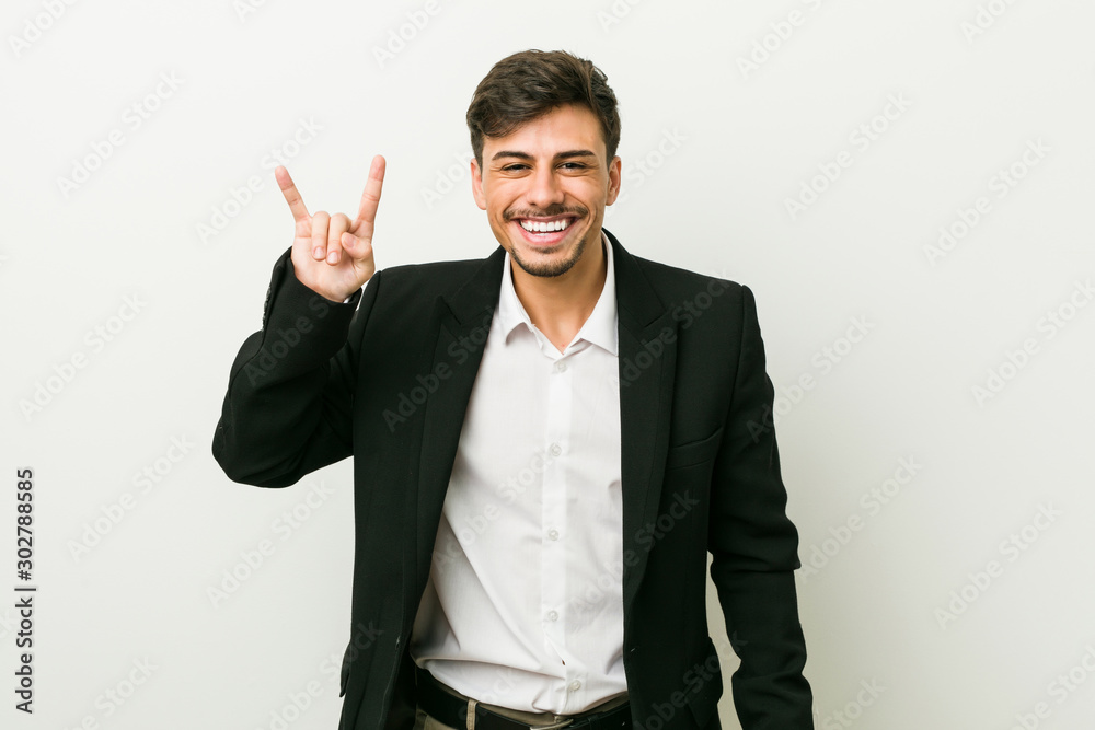 Young business hispanic man showing a horns gesture as a revolution concept. Young business hispanic man showing a horns gesture as a revolution concept.
