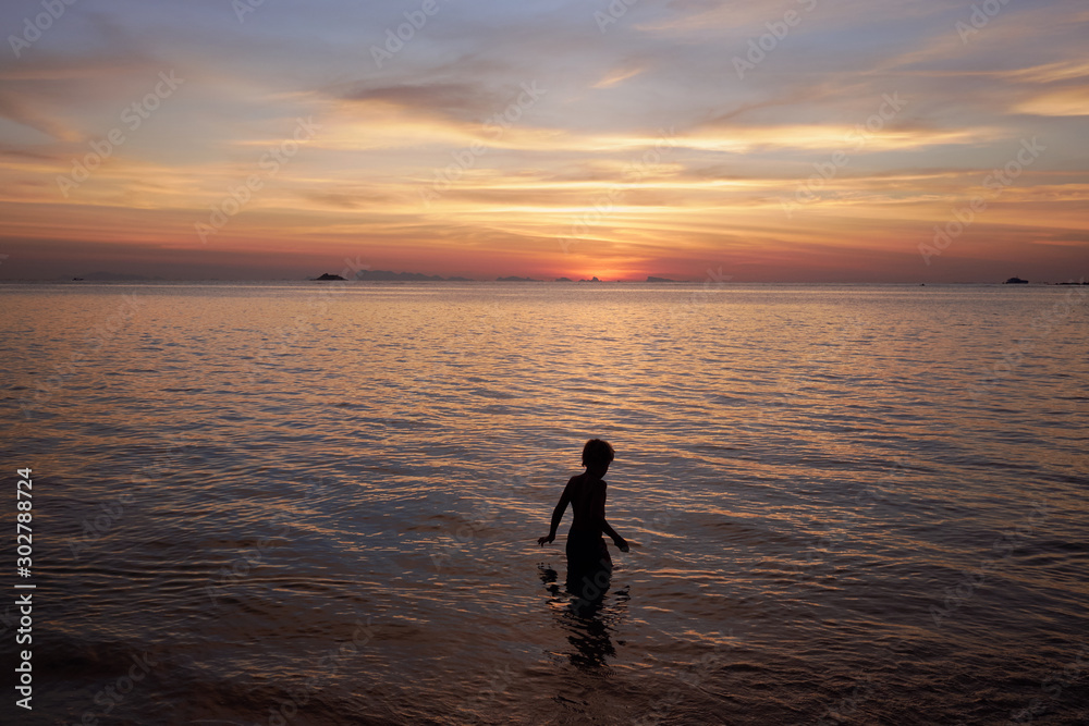 Silhouette of a boy on sunset at the sea