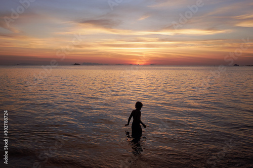 Silhouette of a boy on sunset at the sea