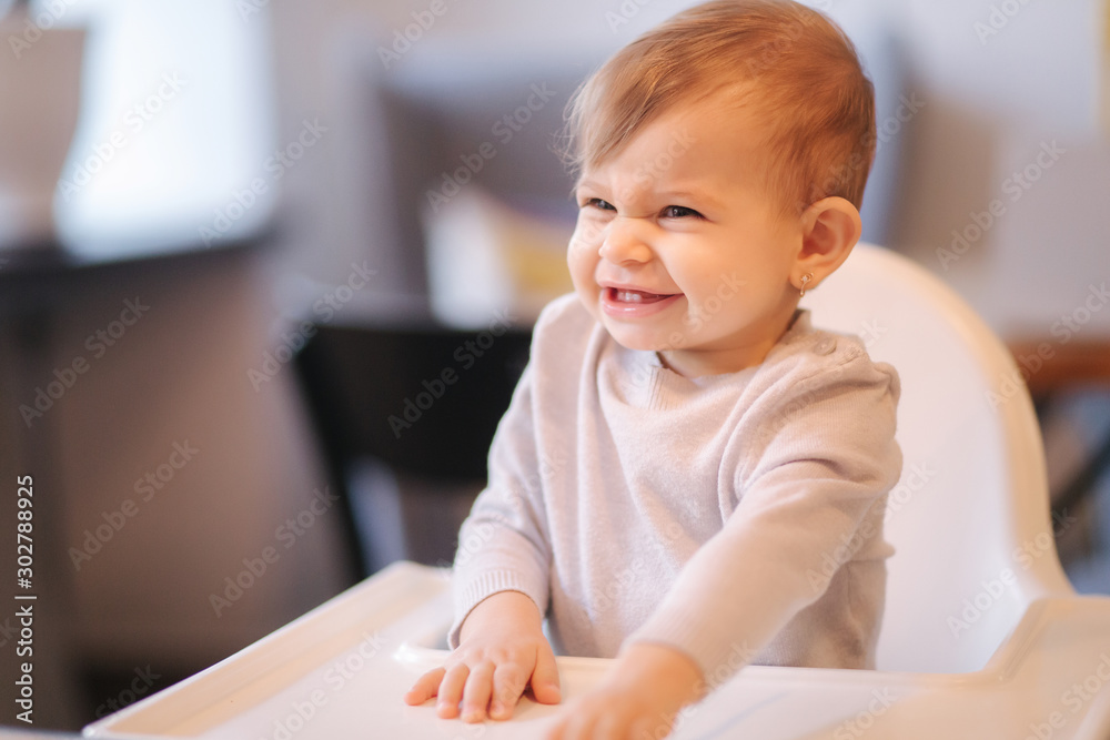 Portrait of adorable little girl on highchair. Baby laughing and play. Happy girl smile Portrait of adorable little girl on highchair. Baby laughing and play. Happy girl smile