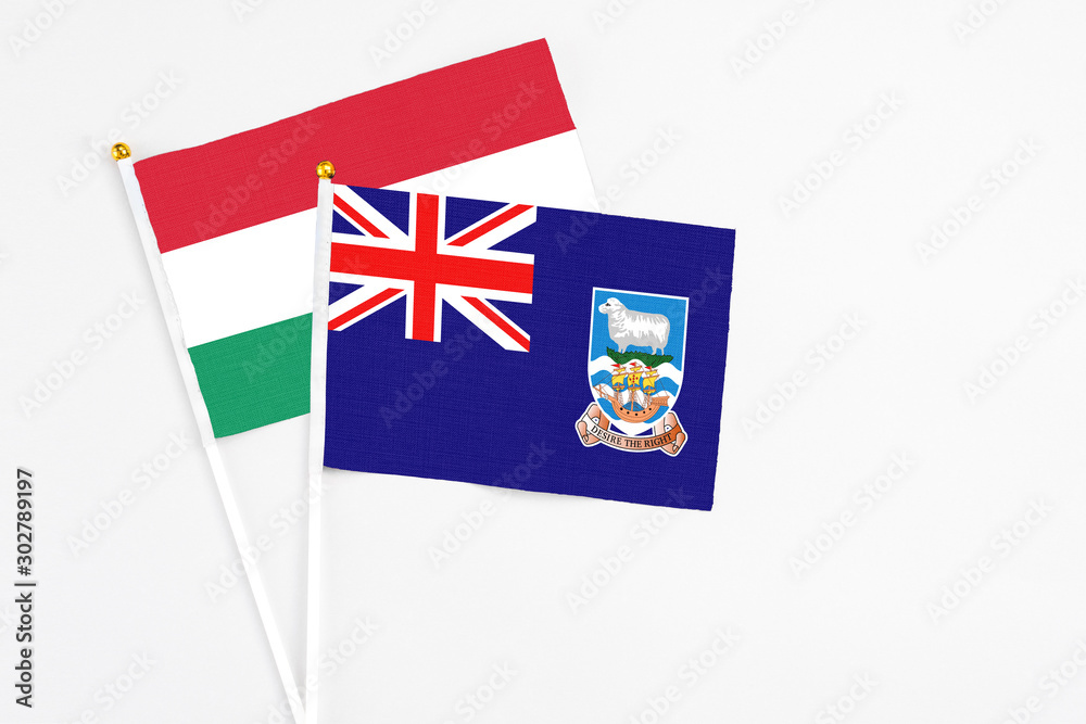 Fototapeta premium Falkland Islands and Hungary stick flags on white background. High quality fabric, miniature national flag. Peaceful global concept.White floor for copy space.