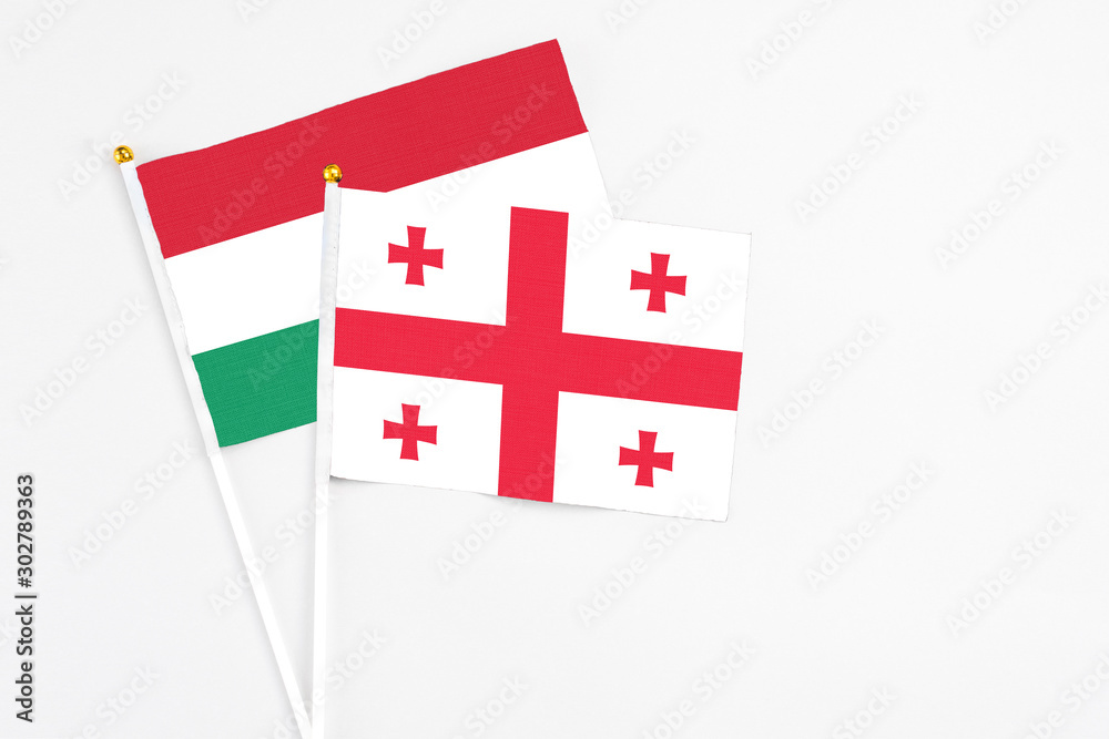 Georgia and Hungary stick flags on white background. High quality fabric, miniature national flag. Peaceful global concept.White floor for copy space.