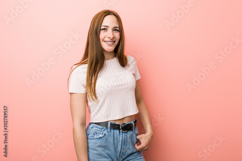 Young redhead ginger woman against a pink wall happy, smiling and cheerful.