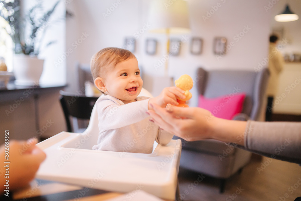 Cute baby girl sitting on highchair in cafe and play with toy Cute baby girl sitting on highchair in cafe and play with toy