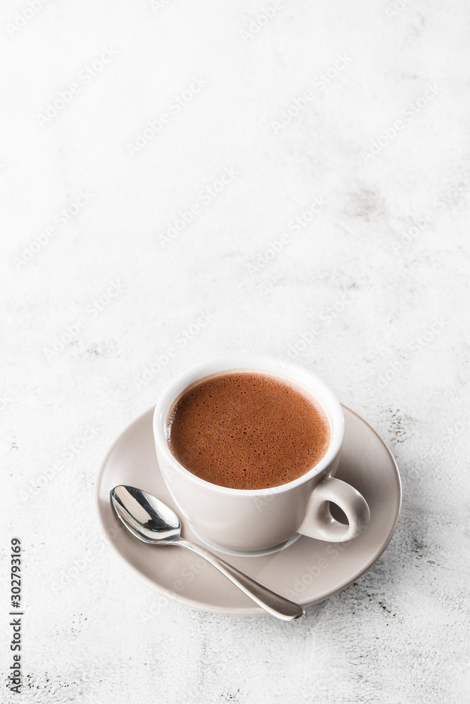 Cup of hot cocoa or hot chocolate or americano in white cup isolated on bright marble background. Overhead view, copy space. Vertical photo. traditional drinks for winter time