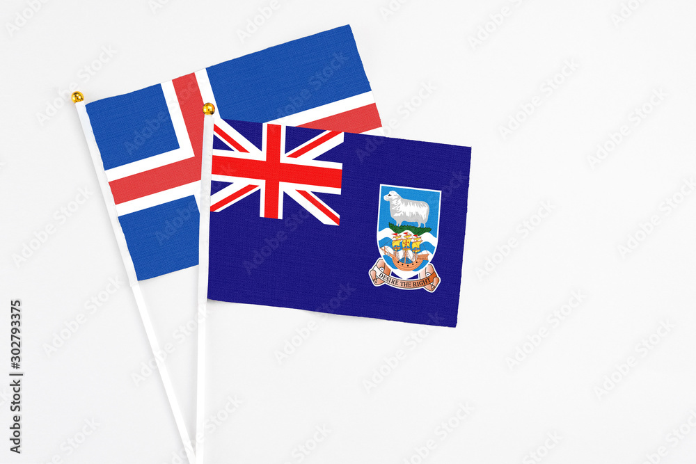 Fototapeta premium Falkland Islands and Iceland stick flags on white background. High quality fabric, miniature national flag. Peaceful global concept.White floor for copy space.