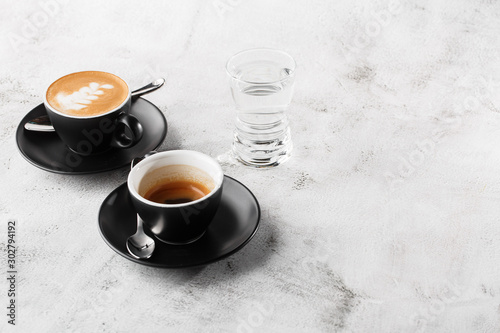 Two dark cups of hot black coffee, espresso, cappuccino with milk isolated on bright marble background. Overhead view, copy space. Advertising for cafe menu. Coffee shop menu. Horizontal photo.