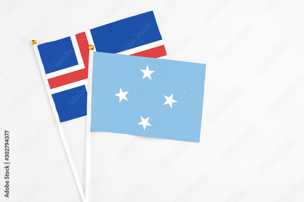 Fototapeta premium Micronesia and Iceland stick flags on white background. High quality fabric, miniature national flag. Peaceful global concept.White floor for copy space.
