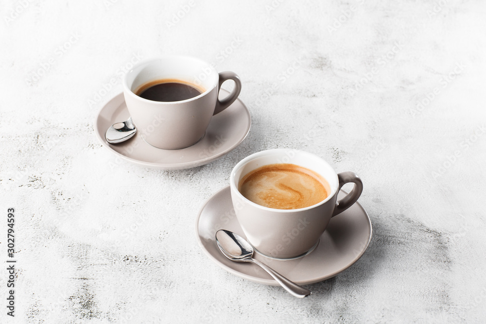Two white cups of hot black coffee with milk isolated on bright marble background. Overhead view, copy space. Advertising for cafe menu. Coffee shop menu. Horizontal photo.