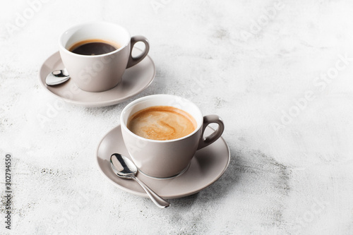 Two white cups of hot black coffee with milk isolated on bright marble background. Overhead view, copy space. Advertising for cafe menu. Coffee shop menu. Horizontal photo.