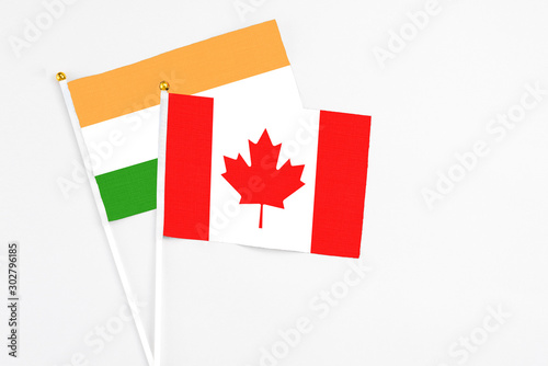 Canada and India stick flags on white background. High quality fabric, miniature national flag. Peaceful global concept.White floor for copy space.