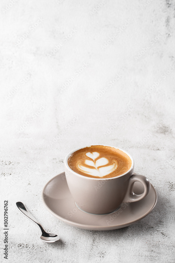 White cup of hot latte coffee with beautiful milk foam latte art texture isolated on bright marble background. Overhead view, copy space. Advertising for cafe menu. Coffee shop menu. Vertical photo.