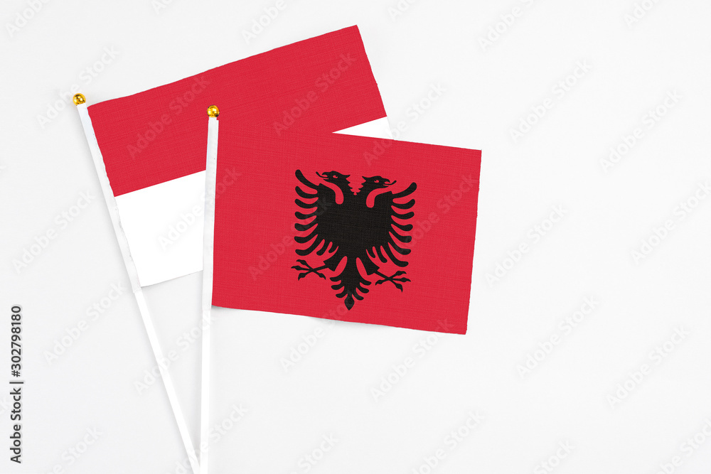 Obraz premium Albania and Indonesia stick flags on white background. High quality fabric, miniature national flag. Peaceful global concept.White floor for copy space.