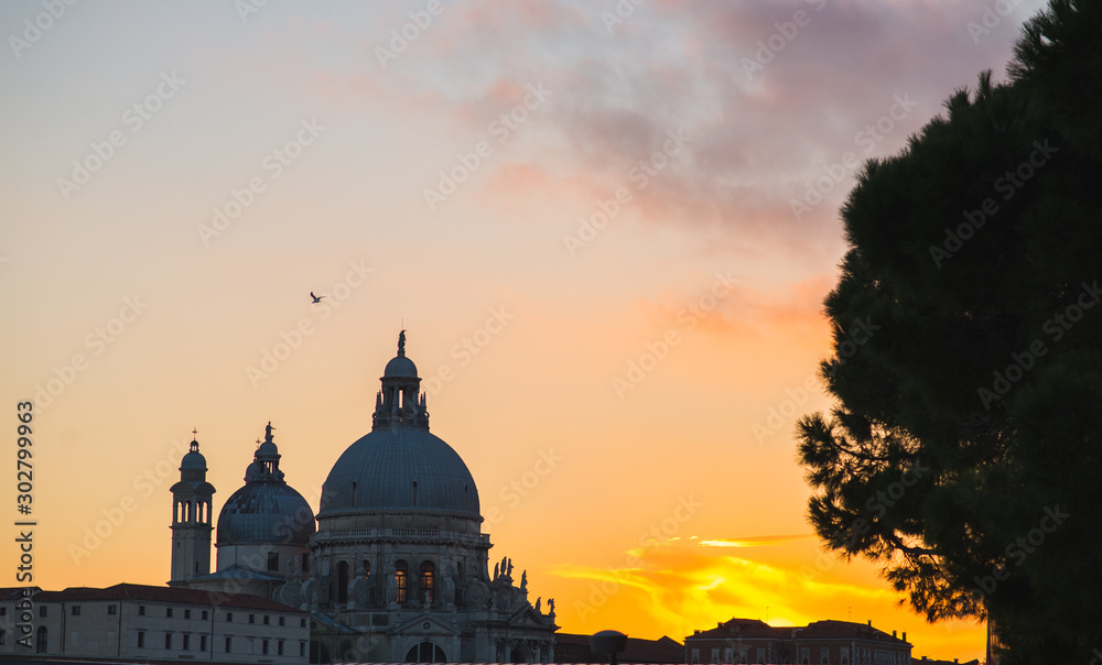View of the Basilica di Santa Maria della Salute and other historic buildings in Venice during sunset.