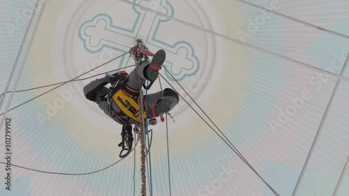 Industrial climber in equipment for high-altitude work working at high altitude in church building. on the climber s belt carabiners. climber high-altitude installation of chandelier and lighting. photo