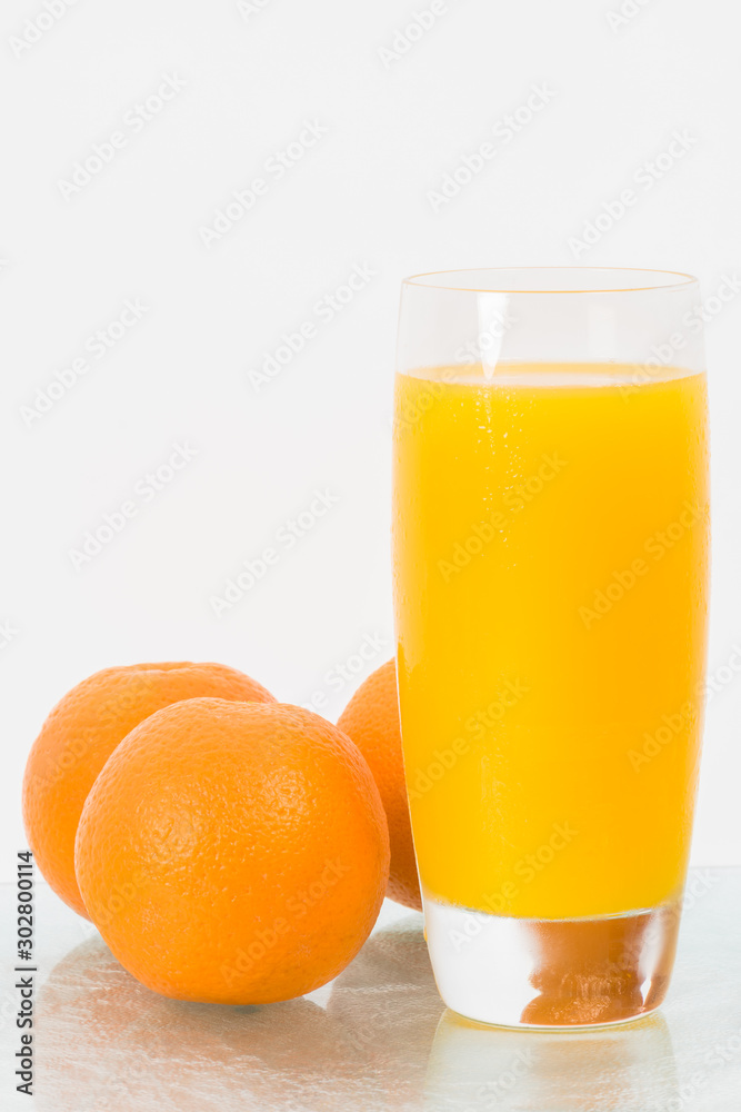 Concept image for healthy living showing a glass of freshly squeezed orange juice and the fruit isolated against a white background. Concept image for healthy living showing a glass of freshly squeezed orange juice and the fruit isolated against a white background.
