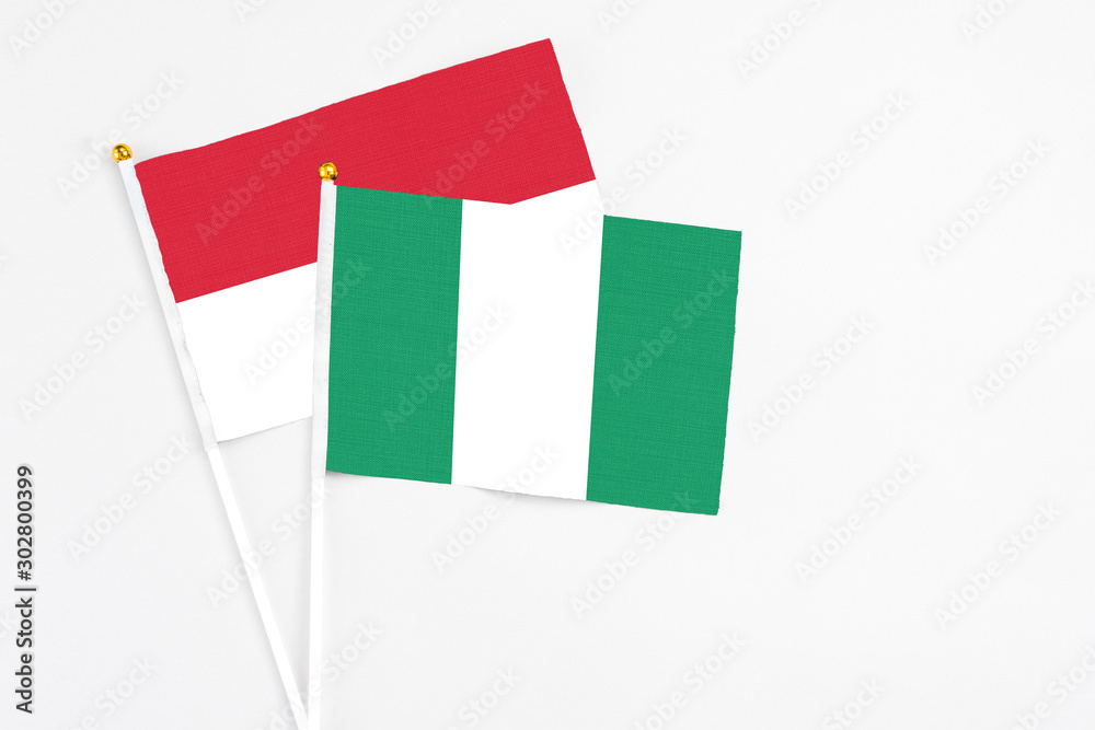 Nigeria and Indonesia stick flags on white background. High quality fabric, miniature national flag. Peaceful global concept.White floor for copy space. Nigeria and Indonesia stick flags on white background. High quality fabric, miniature national flag. Peaceful global concept.White floor for copy space.