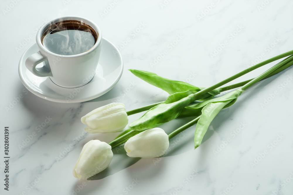 coffee background of a cup of hot black coffee with bunch of white tulip on white marble background coffee background of a cup of hot black coffee with bunch of white tulip on white marble background