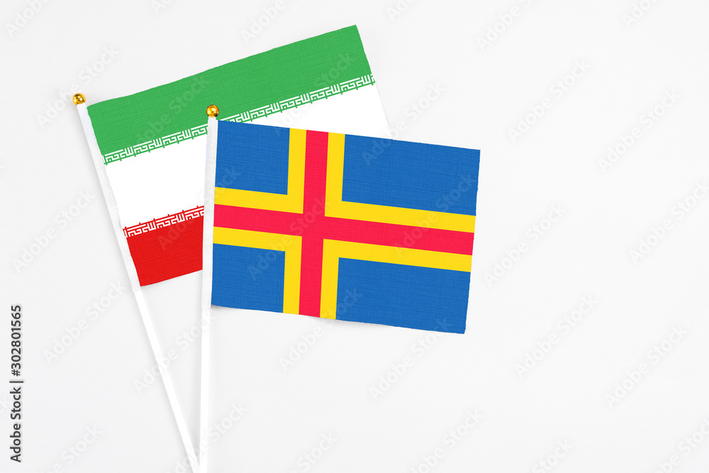 Aland Islands and Iran stick flags on white background. High quality fabric, miniature national flag. Peaceful global concept.White floor for copy space. Aland Islands and Iran stick flags on white background. High quality fabric, miniature national flag. Peaceful global concept.White floor for copy space.