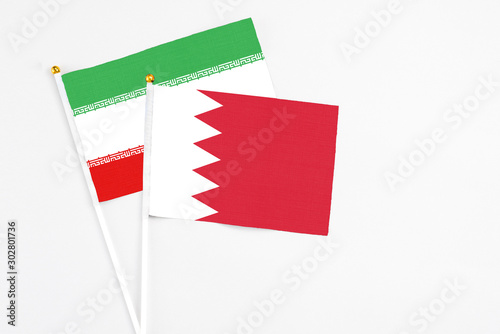 Bahrain and Iran stick flags on white background. High quality fabric, miniature national flag. Peaceful global concept.White floor for copy space.