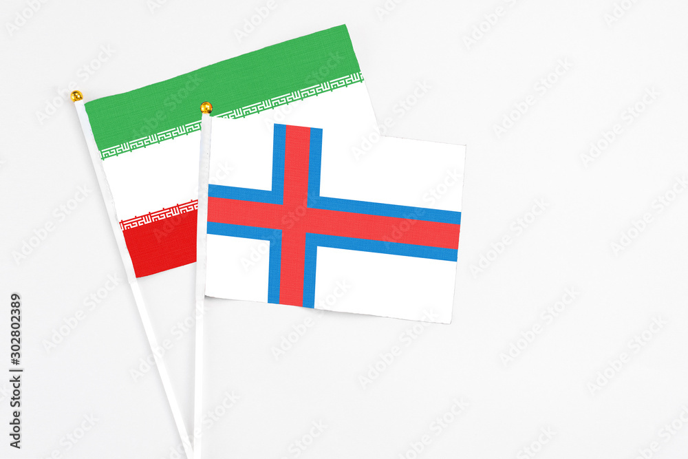 Faroe Islands and Iran stick flags on white background. High quality fabric, miniature national flag. Peaceful global concept.White floor for copy space.