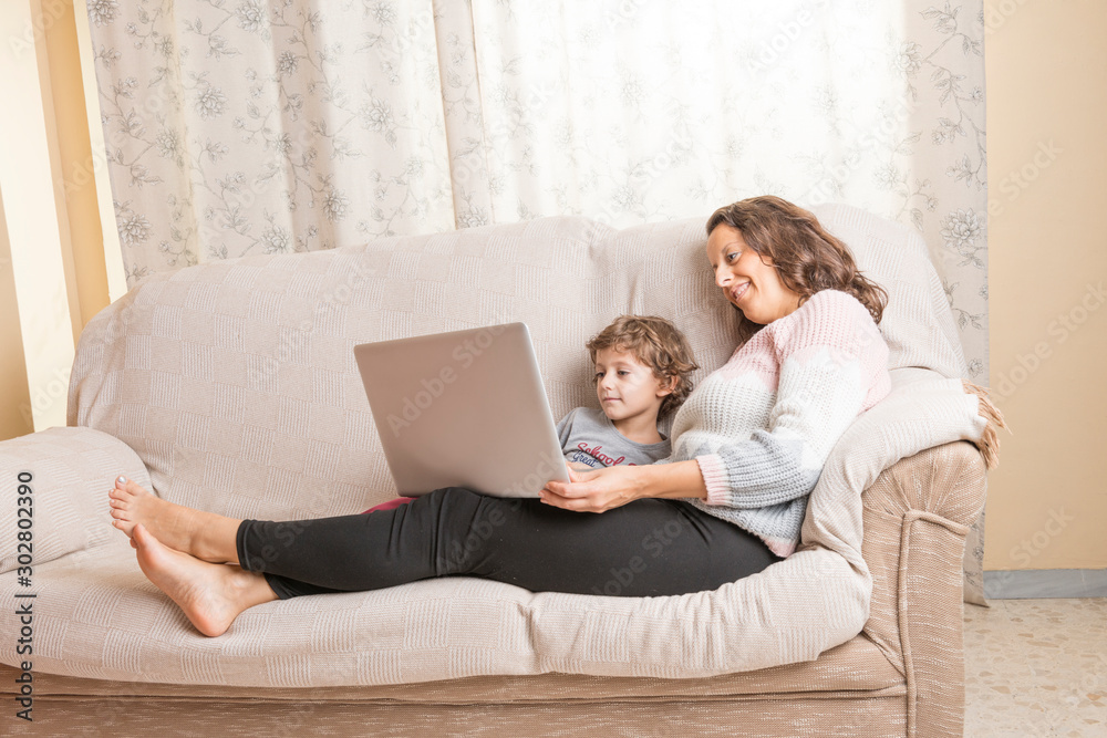 Child and woman sitting on a sofa watching a laptop. Child and woman sitting on a sofa watching a laptop.