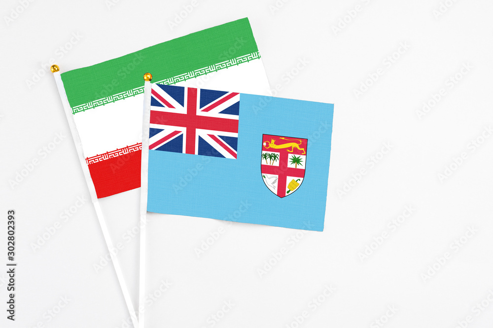 Fototapeta premium Fiji and Iran stick flags on white background. High quality fabric, miniature national flag. Peaceful global concept.White floor for copy space.