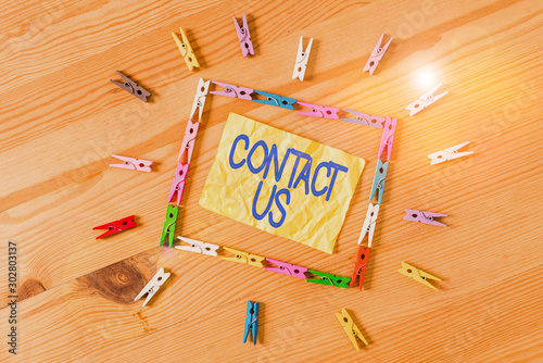 Writing note showing Contact Us. Business concept for Term used to describe reaching out with the business or demonstrating Colored clothespin papers empty reminder wooden floor background office photo