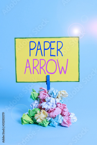 Text sign showing Paper Arrow. Business photo showcasing Business infographic use to show direction or movement Reminder pile colored crumpled paper clothespin reminder blue background