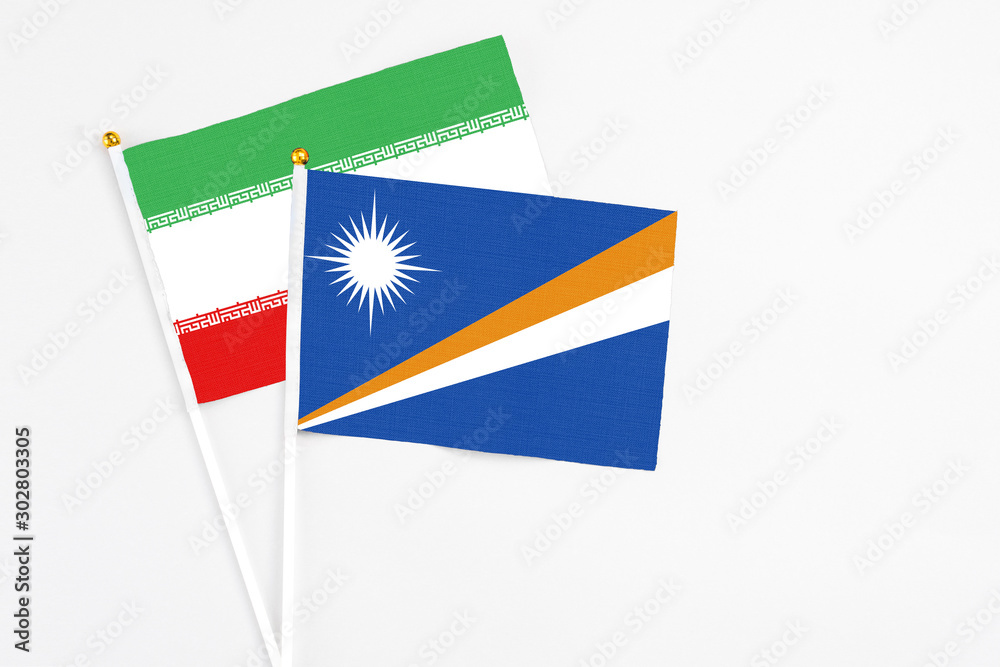 Marshall Islands and Iran stick flags on white background. High quality fabric, miniature national flag. Peaceful global concept.White floor for copy space.